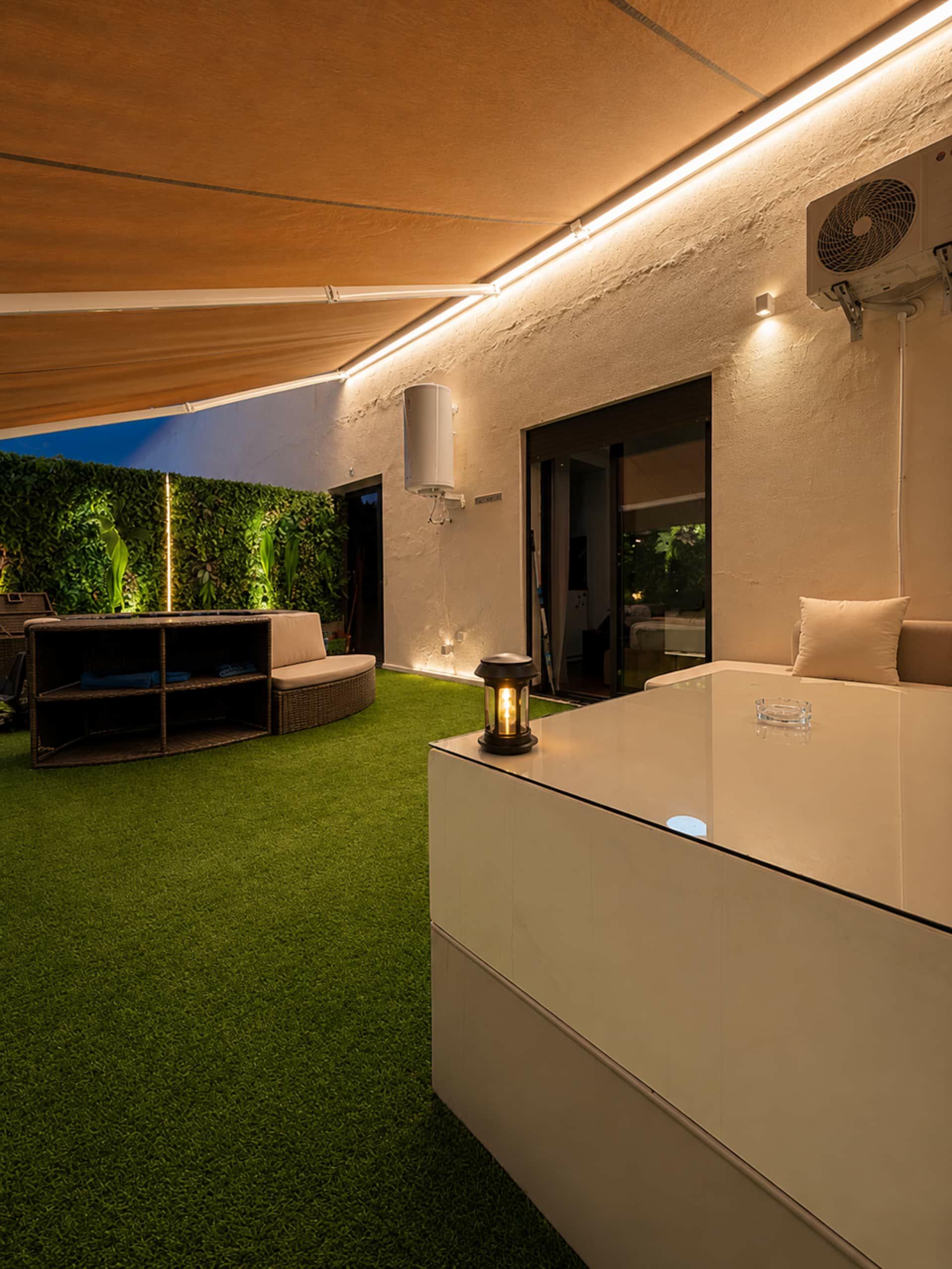 Rincón de salón de la terraza bajo el toldo, a la luz de los farolillos